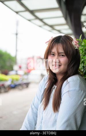 Un portrait vertical moyen d'une heureuse adolescente de grande taille asiatique Isan thaïlandaise du Sud-est souriant à la caméra lors de son voyage de vacances. Elle se tient sur un cit Banque D'Images