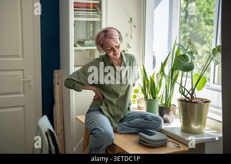 Femme mature joyeuse se relaxant avec un service de streaming audio, écoutant un flux de musique en ligne sur téléphone. Banque D'Images