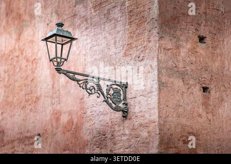 Lanterne vintage ornée montée sur un mur colonial texturé dans les rues historiques de Lima, au Pérou, sous la lumière chaude de l'après-midi Banque D'Images