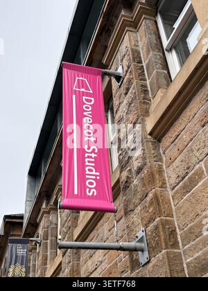 Bannière de marque rose pour Dovecot Studios montée sur un mur de pierre. Édimbourg, Écosse. Banque D'Images