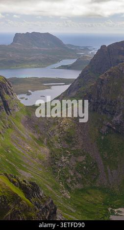 Vallée montagneuse spectaculaire avec des lacs immaculés nichés entre des sommets imposants des Lofoten, Norvège. Paysage alpin accidenté recouvert de mousse Banque D'Images