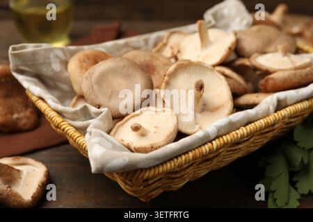 Champignons shiitake crus dans un panier en osier sur une table en bois, gros plan Banque D'Images