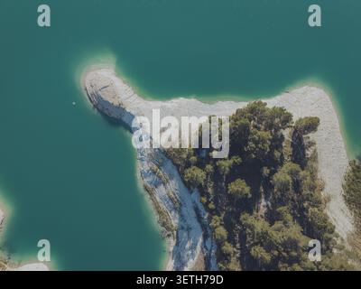 Vue aérienne des eaux turquoises du réservoir Guadalest, avec une péninsule rocheuse couverte de pins s'étendant dans l'eau, Alicante, Valen Banque D'Images