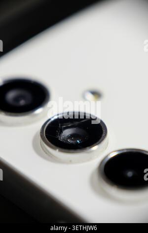 Photo macro d'un objectif d'appareil photo de smartphone fissuré et cassé sur un fond blanc avec mise au point sélective Banque D'Images