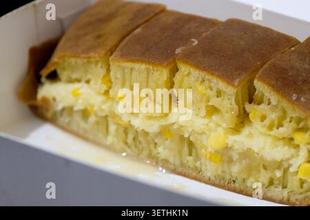 Délicieux fromage manis martabak et garniture de maïs sucré, dessert traditionnel indonésien de rue sucré tranché sur une boîte à emporter Banque D'Images