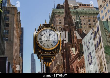 New York City, États-Unis – 16 juin 2026 : horloge de trottoir ornée de la Trump Tower avec l'église presbytérienne de la Cinquième Avenue en arrière-plan. Banque D'Images