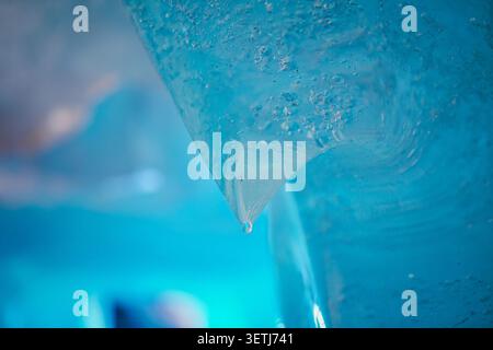 Vue de formations de glace fondante avec une seule gouttelette d'eau suspendue à un bord tranchant du glacier du Rhône à Obergoms, Valais, Suisse. Banque D'Images