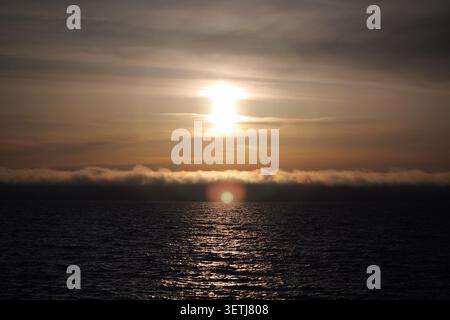 Vue sur le coucher de soleil sur la mer Baltique avec une basse banque de nuages et l'eau chatoyante à Liepaja, Lettonie. Banque D'Images