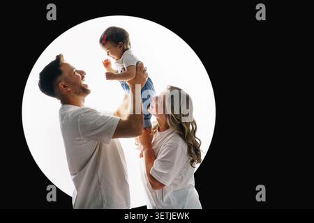 Une famille joyeuse avec un bébé heureux. Les parents sourient et regardent leur fille avec amour. Concept « Focus on the Family » Banque D'Images