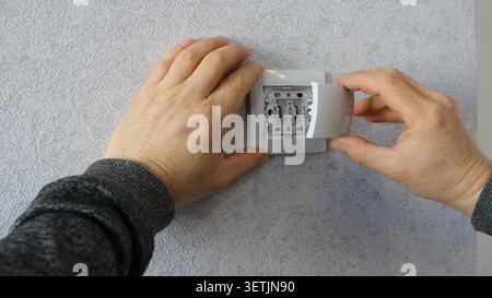 La dernière étape de l'installation ou du remplacement d'un composant électrique domestique, d'un interrupteur ou d'une prise dans un intérieur, le moment précis de l'assemblage Banque D'Images