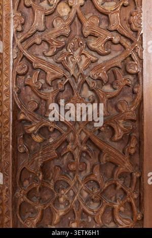 Panneau en bois sculpté à la main orné de motifs arabesques floraux complexes et de détails en relief. Les tons bruns chauds et la texture tactile véhiculent les artisans Banque D'Images