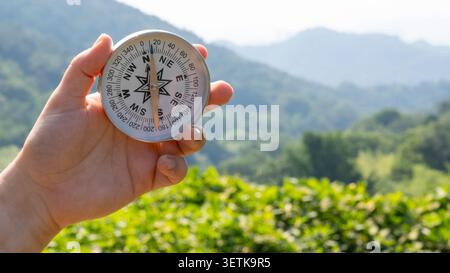 Boussole ronde en main sur le fond de montagne floue. Concept pour voyager Banque D'Images