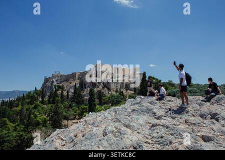Athènes, Grèce. 21 juin 2026. Les visiteurs se tiennent sur la colline d'Aréopage surplombant l'Acropole à Athènes, en Grèce, le 21 juin 2026. L'Acropole, site classé au patrimoine mondial de l'UNESCO, est l'un des monuments archéologiques les plus visités de Grèce. Athènes attire des millions de touristes chaque année, en particulier pendant la saison estivale, malgré les périodes de chaleur extrême. (Photo de Elvis Takahashi Mantello/Middle East images/StringersHub/SIPA USA) crédit : SIPA USA/Alamy Live News Banque D'Images
