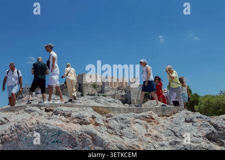 Athènes, Grèce. 21 juin 2026. Les touristes traversent la colline d'Aréopage surplombant l'Acropole à Athènes, en Grèce, le 21 juin 2026. L'Acropole, site classé au patrimoine mondial de l'UNESCO, est l'un des monuments archéologiques les plus visités de Grèce. Athènes attire des millions de touristes chaque année, en particulier pendant la saison estivale, malgré les périodes de chaleur extrême. (Photo de Elvis Takahashi Mantello/Middle East images/StringersHub/SIPA USA) crédit : SIPA USA/Alamy Live News Banque D'Images