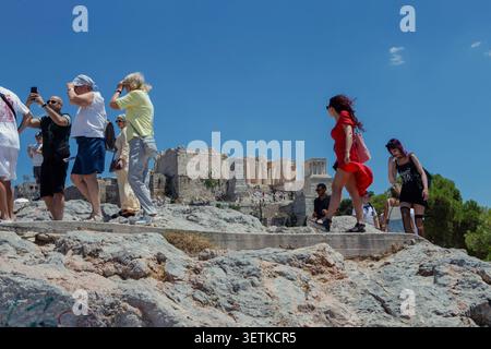 Athènes, Grèce. 21 juin 2026. Les touristes traversent la colline d'Aréopage surplombant l'Acropole à Athènes, en Grèce, le 21 juin 2026. L'Acropole, site classé au patrimoine mondial de l'UNESCO, est l'un des monuments archéologiques les plus visités de Grèce. Athènes attire des millions de touristes chaque année, en particulier pendant la saison estivale, malgré les périodes de chaleur extrême. (Photo de Elvis Takahashi Mantello/Middle East images/StringersHub/SIPA USA) crédit : SIPA USA/Alamy Live News Banque D'Images