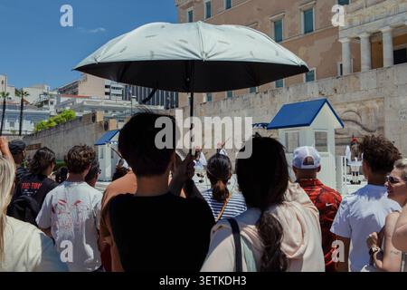 Athènes, Grèce. 21 juin 2026. Les touristes se rassemblent devant le bâtiment du Parlement hellénique sur la place Syntagma à Athènes, Grèce, le 21 juin 2026. La Grèce a connu des températures estivales élevées alors qu'une vague de chaleur a affecté certaines parties du pays. Les autorités ont exhorté les résidents et les visiteurs à prendre des précautions contre les risques liés à la chaleur, tandis que les sites touristiques populaires à Athènes continuaient d'attirer un grand nombre de visiteurs. (Photo de Elvis Takahashi Mantello/Middle East images/StringersHub/SIPA USA) crédit : SIPA USA/Alamy Live News Banque D'Images