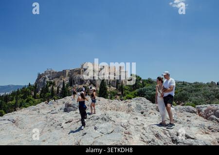 Athènes, Grèce. 21 juin 2026. Les visiteurs se tiennent sur la colline d'Aréopage surplombant l'Acropole à Athènes, en Grèce, le 21 juin 2026. L'Acropole, site classé au patrimoine mondial de l'UNESCO, est l'un des monuments archéologiques les plus visités de Grèce. Athènes attire des millions de touristes chaque année, en particulier pendant la saison estivale, malgré les périodes de chaleur extrême. (Photo de Elvis Takahashi Mantello/Middle East images/StringersHub/SIPA USA) crédit : SIPA USA/Alamy Live News Banque D'Images