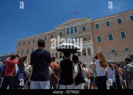 Athènes, Grèce. 21 juin 2026. Les touristes se rassemblent devant le bâtiment du Parlement hellénique sur la place Syntagma à Athènes, Grèce, le 21 juin 2026. La Grèce a connu des températures estivales élevées alors qu'une vague de chaleur a affecté certaines parties du pays. Les autorités ont exhorté les résidents et les visiteurs à prendre des précautions contre les risques liés à la chaleur, tandis que les sites touristiques populaires à Athènes continuaient d'attirer un grand nombre de visiteurs. (Photo de Elvis Takahashi Mantello/Middle East images/StringersHub/SIPA USA) crédit : SIPA USA/Alamy Live News Banque D'Images