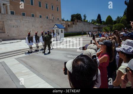 Athènes, Grèce. 21 juin 2026. Les touristes regardent la cérémonie de la relève de la garde devant le bâtiment du Parlement hellénique sur la place Syntagma à Athènes, Grèce, le 21 juin 2026. Les gardes de cérémonie des Evzones sont stationnés sur la tombe du soldat inconnu devant le Parlement grec et sont une attraction majeure pour les visiteurs de la capitale grecque. Athènes reste l'une des destinations touristiques les plus visitées du pays pendant la saison estivale. (Photo de Elvis Takahashi Mantello/Middle East images/StringersHub/SIPA USA) crédit : SIPA USA/Alamy Live News Banque D'Images