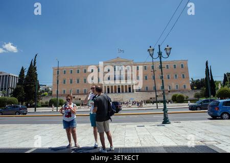 Athènes, Grèce. 21 juin 2026. Les touristes se tiennent devant le bâtiment du Parlement hellénique sur la place Syntagma à Athènes, Grèce, le 21 juin 2026. Athènes a accueilli un grand nombre de visiteurs pendant la saison touristique estivale car la Grèce a connu des températures élevées dans toute une partie du pays. Les touristes doivent prendre des précautions contre les risques liés à la chaleur pendant les périodes de conditions météorologiques extrêmes. (Photo de Elvis Takahashi Mantello/Middle East images/StringersHub/SIPA USA) crédit : SIPA USA/Alamy Live News Banque D'Images