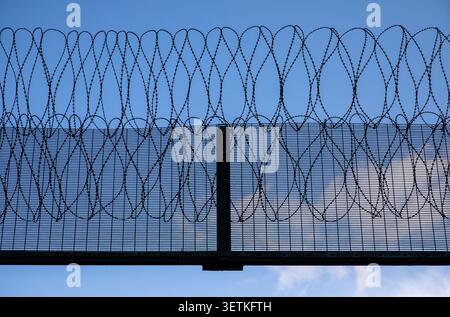 Barrière de sécurité barbelée de prison représentant le système pénal, la protection, le confinement, l'accès restreint et la sécurité Banque D'Images