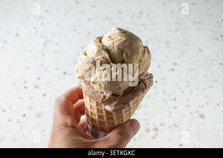Une vue d'une main tenant une glace à deux boules. Banque D'Images