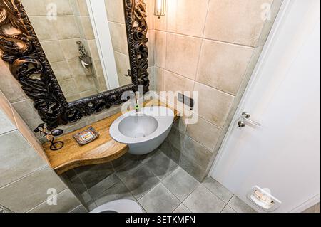 Salle de bains élégante avec miroir noir sculpté, lavabo unique et murs carrelés Banque D'Images