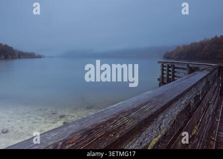111 aube sur les eaux transparentes et vert clair du lac brumeux Bohinj vu du quai de bois pour les bateaux panoramiques sur la rive sud. Ribcev Laz-Slovénie Banque D'Images
