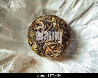 Boule de thé pu-erh chinoise sur papier d'emballage décoratif. Produit de thé fermenté traditionnel avec un aspect authentique artisanal. Banque D'Images