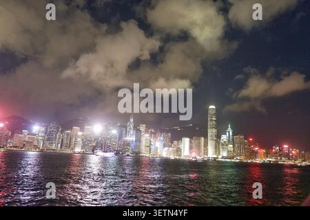 HONG KONG - 18 JUILLET 2023 : le port de Victoria la nuit avec les gratte-ciel illuminés de l'île de Hong Kong et les ferries qui passent. Banque D'Images