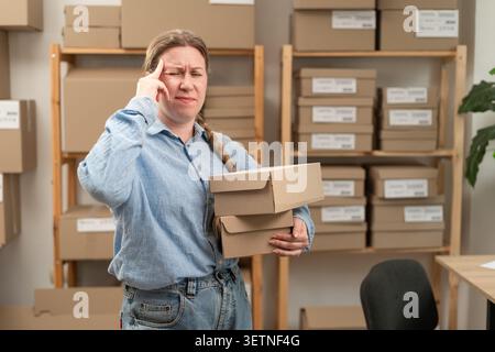 Malade débutant de petites entreprises PME propriétaire femme souffrant de maux de tête et de migraine avec des commandes en ligne dans des boîtes. copier l'espace Banque D'Images