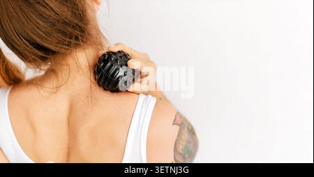 Femme utilisant la boule de massage pour le cou haut du dos Banque D'Images