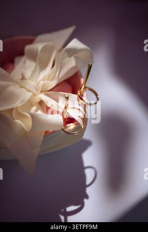 Plan macro de bandes d'or classiques reposant sur des décorations élégantes avec des pétales de fleurs ivoire doux, évoquant des sentiments de romance, d'amour éternel et de luxe c Banque D'Images