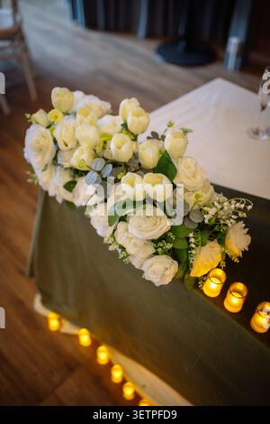 Gros plan romantique d'un luxueux arrangement floral avec roses blanches crémeuses, tulipes blanches, eucalyptus délicats et lis de la vallée Banque D'Images
