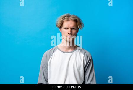Jeune homme frustré regardant stressé, montrant l'irritation et l'expression négative, éprouvant de la gêne, la colère et le mécontentement contre un vibrant Banque D'Images