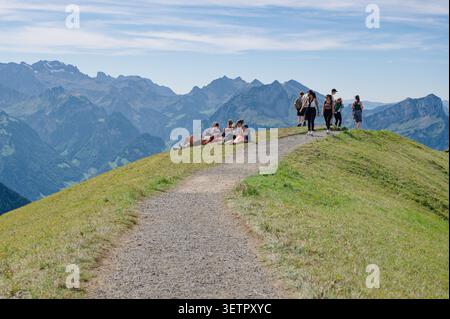 Deux groupes sur la crête de la crête de Stoos - certains reposent sur l'herbe, d'autres marchent vers l'horizon alpin sans fin Banque D'Images