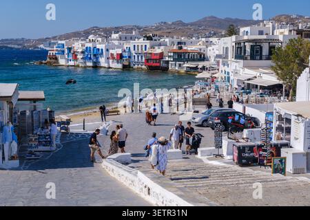 Promenade au bord de l'eau et plage à Mykonos avec des bâtiments blanchis à la chaux, des bateaux et des touristes, Mykonos, Grèce Banque D'Images