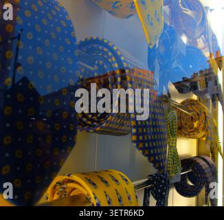 Vue rapprochée d'une vitrine de magasin présentant des cravates soigneusement disposées dans des tons bleus et jaunes avec divers motifs. Banque D'Images
