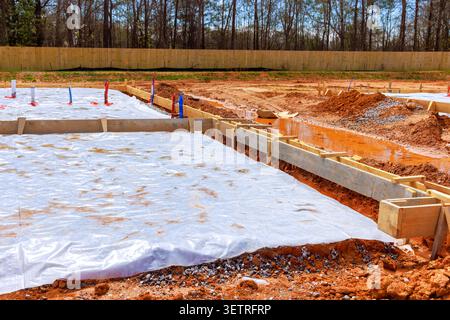 Les ouvriers de la construction préparent la fondation de dalle avec des feuilles de plastique de cadres en bois sur le lot de terre Banque D'Images