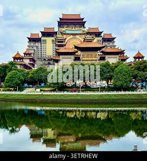 Grand complexe de palais chinois avec des toits de pagode dorés et une architecture traditionnelle ornée reflétée dans l'eau calme, Yuin, Guangxi, Chine Banque D'Images