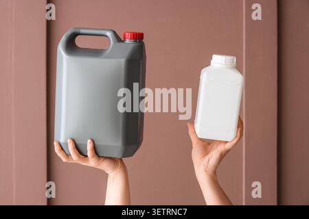 Mains tenant de grands contenants en plastique gris et de petits contenants blancs Banque D'Images