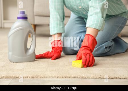 Personne nettoyant le tapis avec une éponge et des gants Banque D'Images