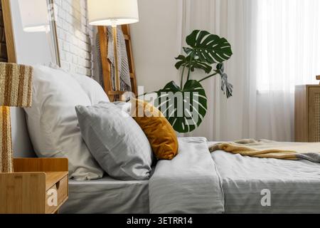 Intérieur de chambre moderne confortable avec lit soigneusement fait et oreillers décoratifs Banque D'Images