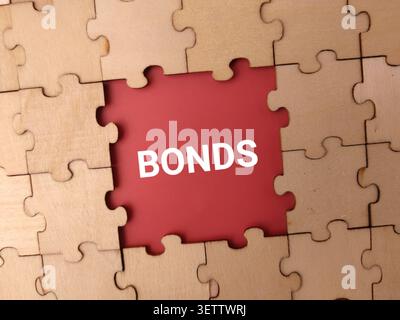 Une pièce centrale manquante dans un puzzle en bois révèle une surface rouge imprimée avec le mot BONDS. Banque D'Images