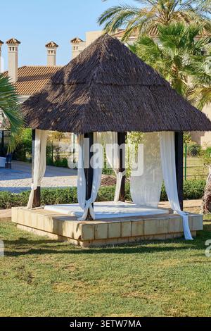 Gazebo avec une chaise longue sur une pelouse verte. Espagne. Banque D'Images