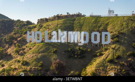 Vue aérienne de l'emblématique panneau Hollywood situé sur les pentes escarpées du mont Lee, entouré d'une végétation sèche et d'un ciel bleu clair à Los Angeles, Banque D'Images