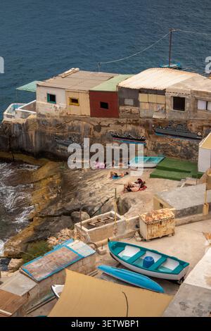 Malte, la Valette, Wuestenwinds Beach visiteurs bronzant à côté de petites propriétés de pêcheurs en bord de mer, en contrebas du Bastion St Christopher Banque D'Images