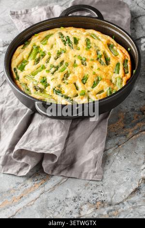 Asperges saines et frittata aux herbes en gros plan dans la poêle. Vertical Banque D'Images