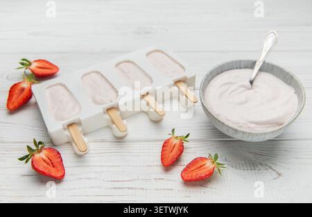 Popsicles au yaourt aux fraises dans un moule avec des baies fraîches et du yaourt crémeux sur une table en bois Banque D'Images