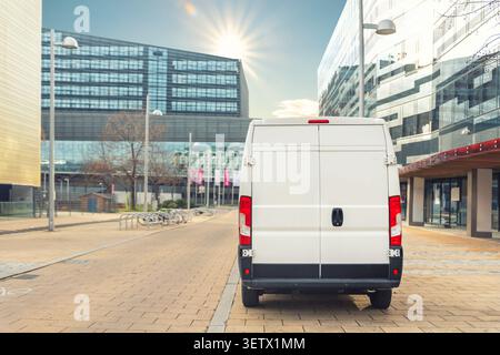 Petite fourgonnette de livraison de marchandises conduisant dans le quartier central de la ville européenne. Camion moyen minifourgonnette véhicule de messagerie livrer le colis au bureau résidentiel Banque D'Images